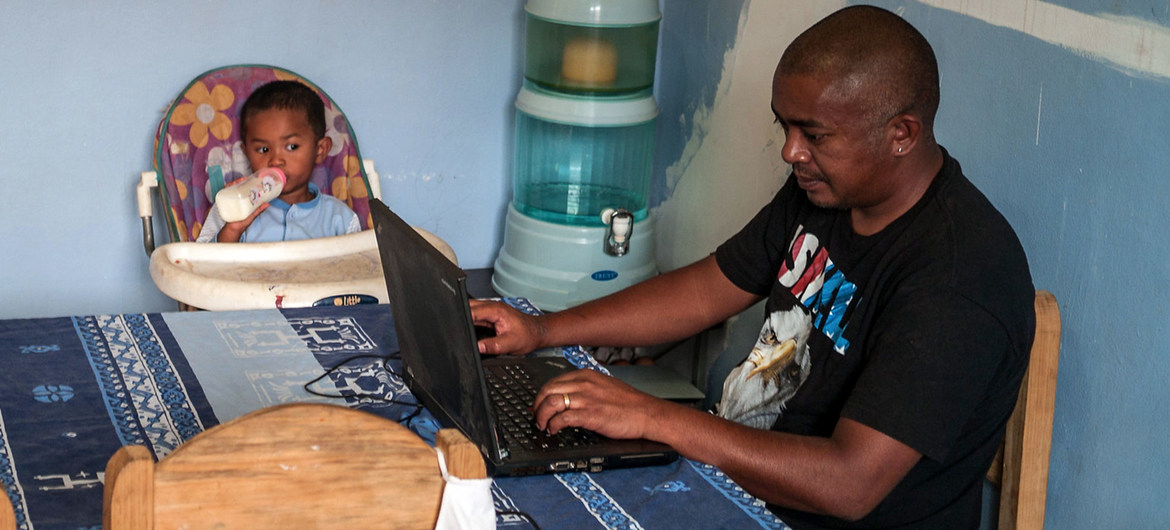 Banco Muncial/Henitsoa Rafalia. Un hombre cuida a su hijo mientras trabaja desde la casa en Madagascar.